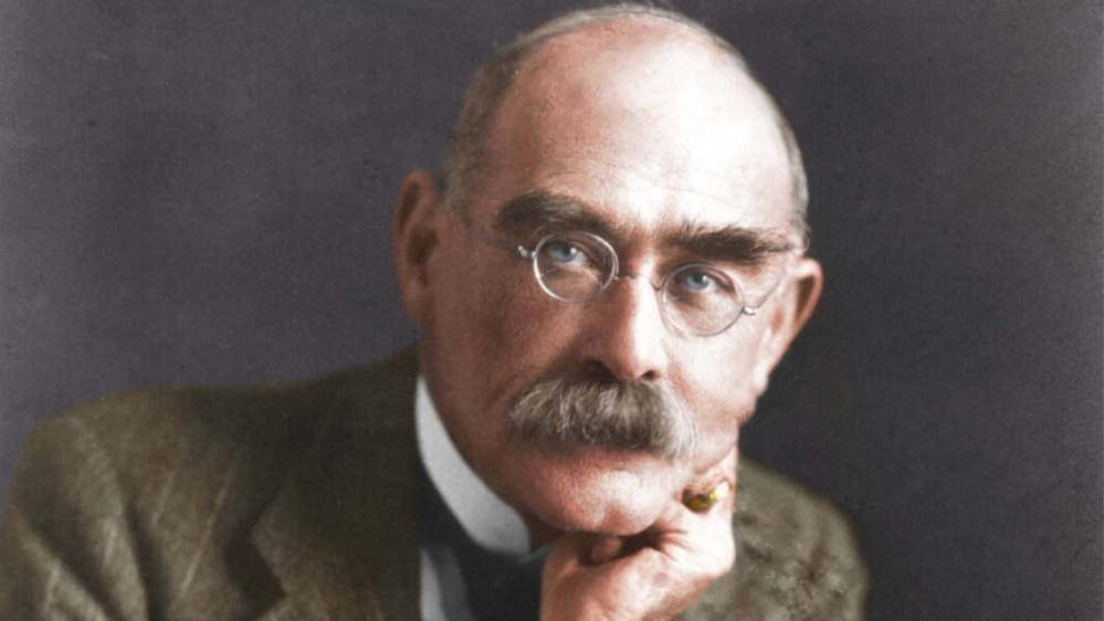 Elderly man with glasses, mustache, resting chin on hand.