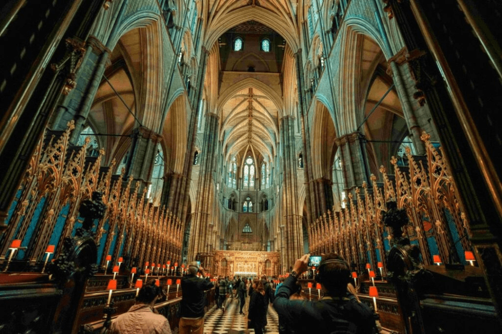 Interior of a gothic cathedral with ornate columns and people taking photos.