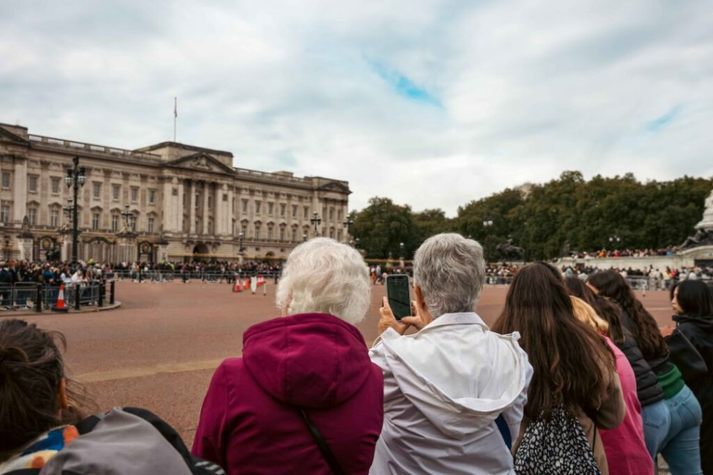 Crowd photographing Buckingham Palace on a cloudy day