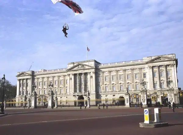 Parachuter descending near a large palace with a flag.