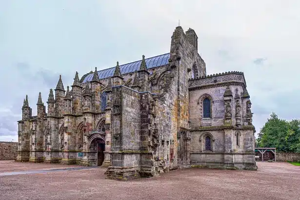 Historic stone church with intricate carvings and towers under a cloudy sky.
