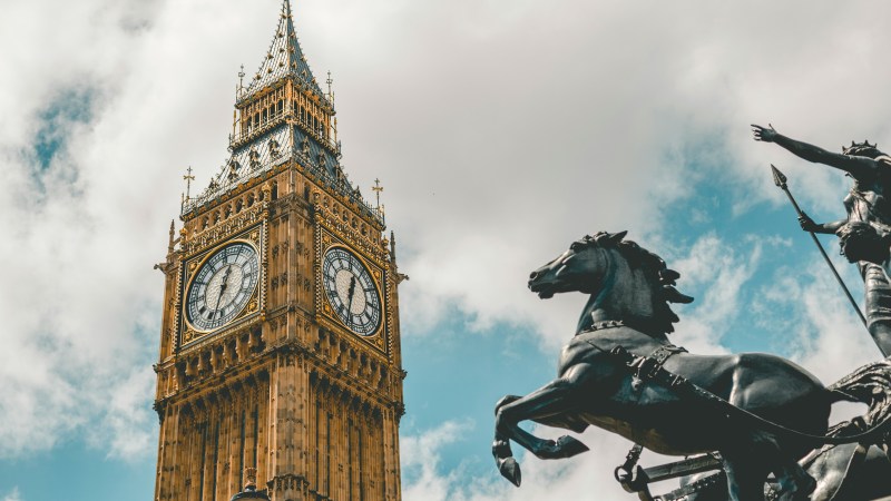 Big Ben tower against cloudy sky with statue of horse and rider in foreground.