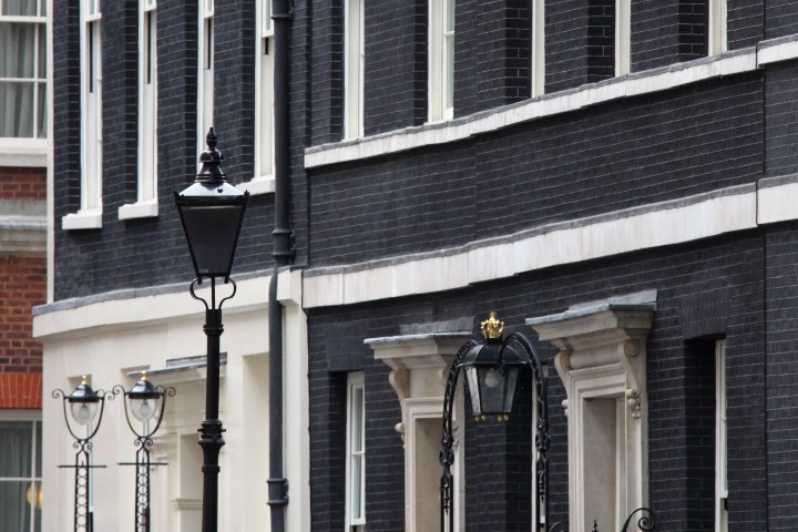 Black-brick building facade with lamppost on a city street.