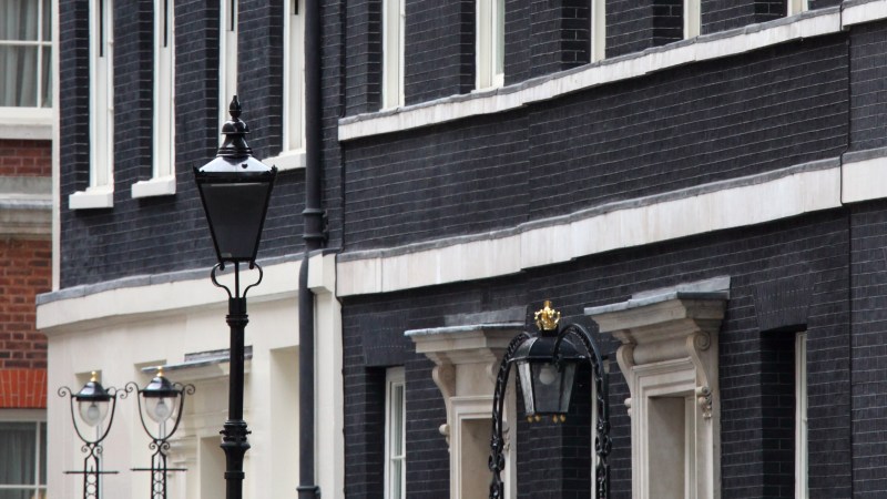 Black-brick building facade with lamppost on a city street.