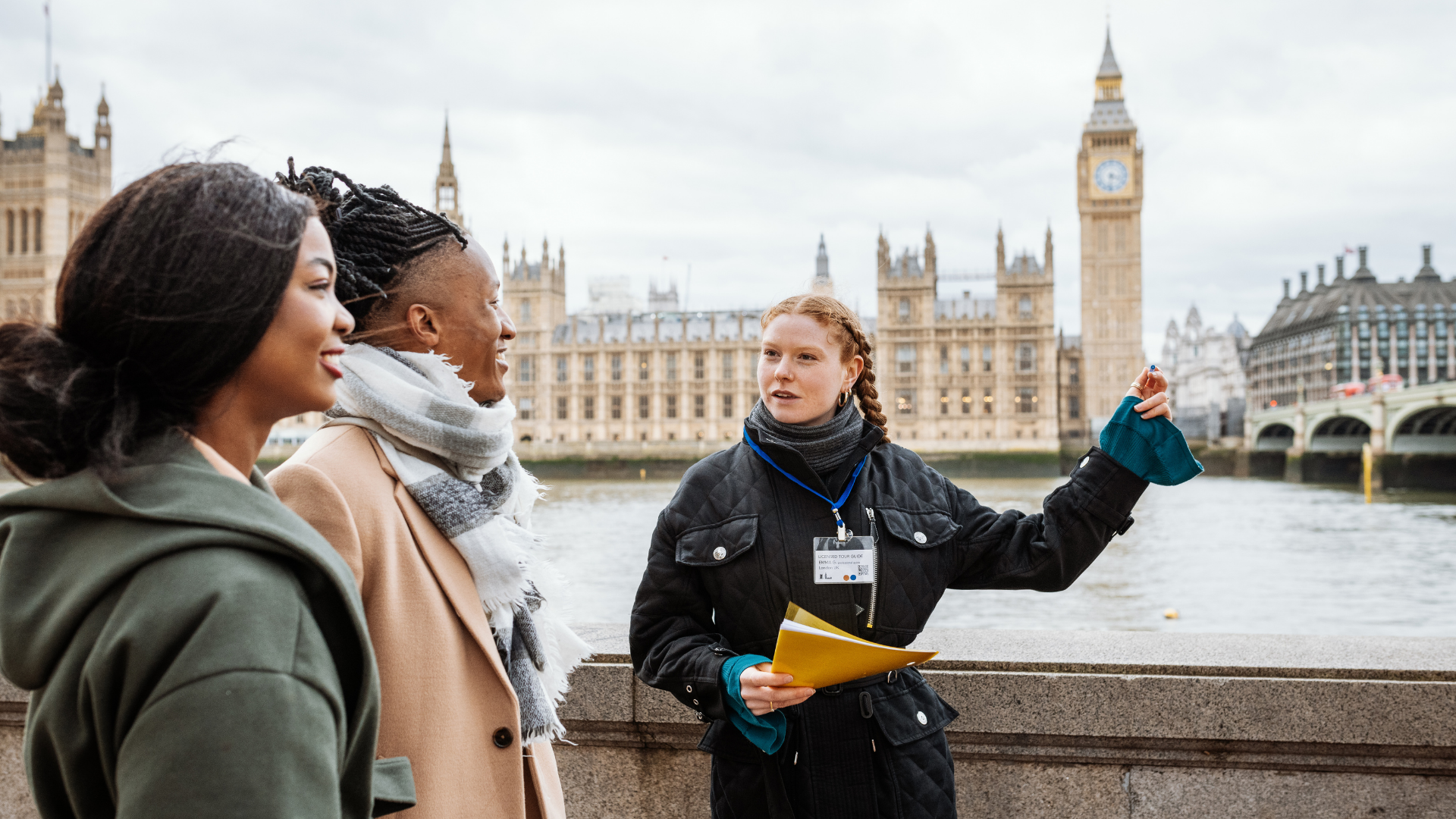 Guide showing tourists Big Ben across the river in London.