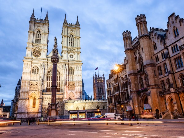Gothic cathedral with twin towers under a cloudy sky, surrounded by historic buildings.
