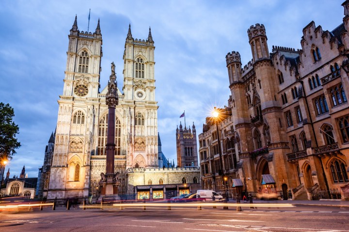Gothic cathedral with twin towers under a cloudy sky, surrounded by historic buildings.