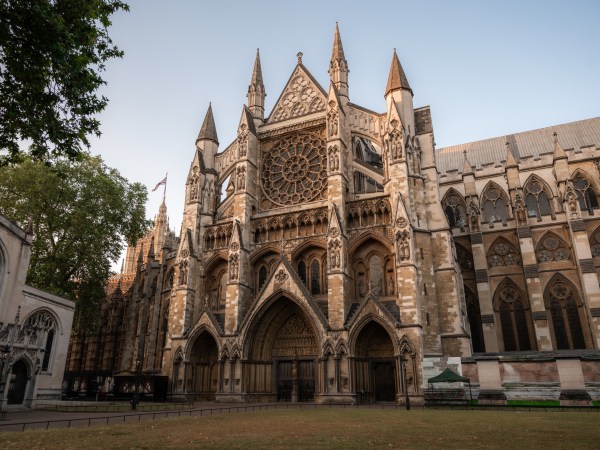 Gothic cathedral facade with rose window and arches at sunset.