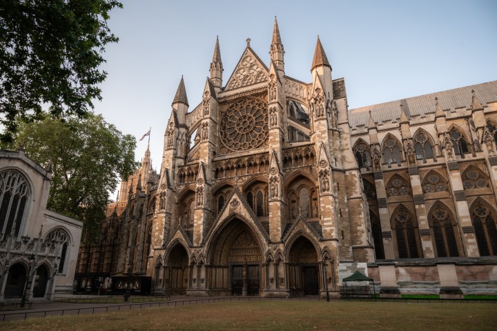 Gothic cathedral facade with rose window and arches at sunset.