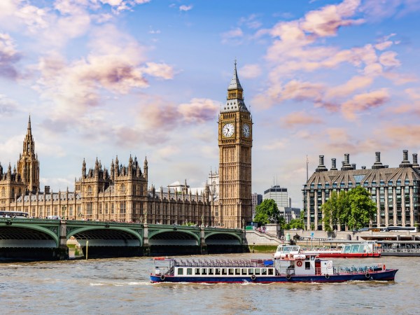 View of Big Ben, Westminster Bridge, and boats on the River Thames in London.