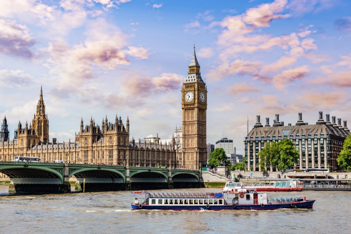 View of Big Ben, Westminster Bridge, and boats on the River Thames in London.