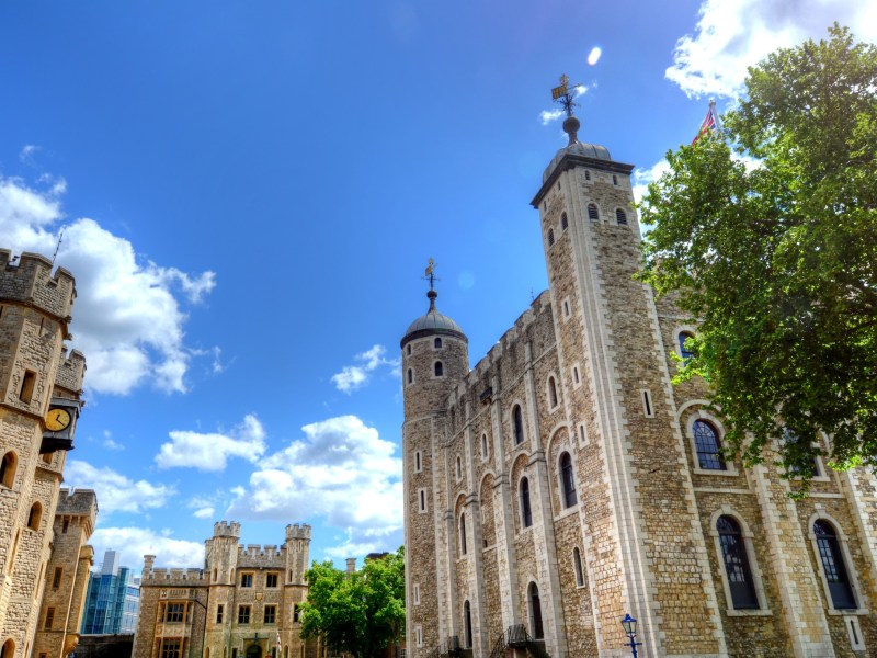 The Tower of London against a blue sky with scattered clouds.