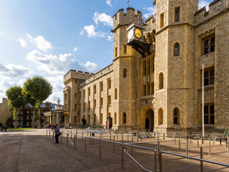 Historic stone castle with clock tower, blue sky background.