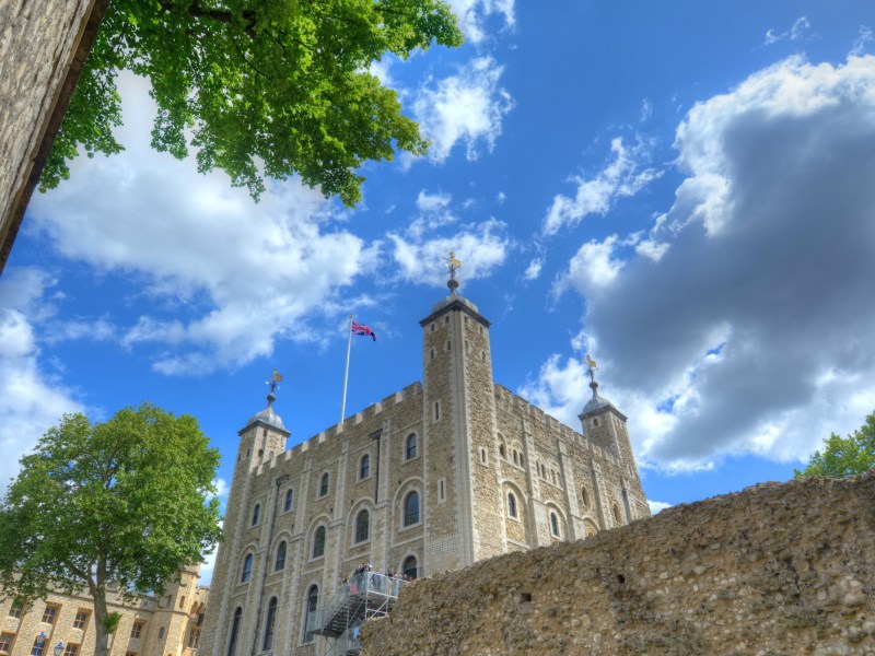 Historic stone castle with towers under a partly cloudy blue sky.