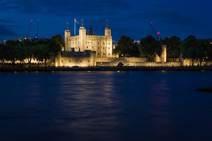 Tower of London illuminated at night, viewed across the River Thames.